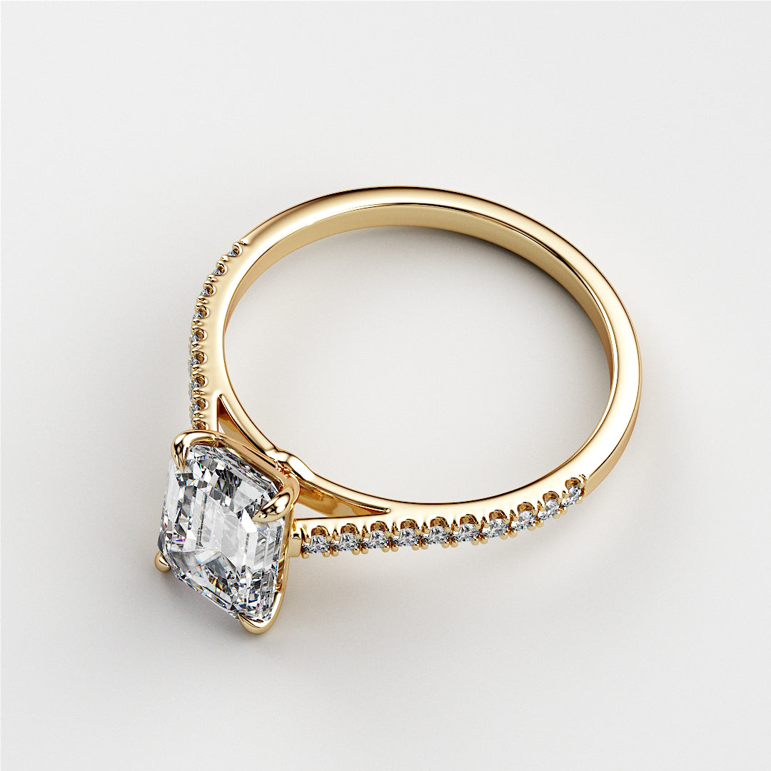Close-up of a stunning 14K and 18K yellow gold engagement ring featuring an Asscher-cut emerald and delicate diamonds.