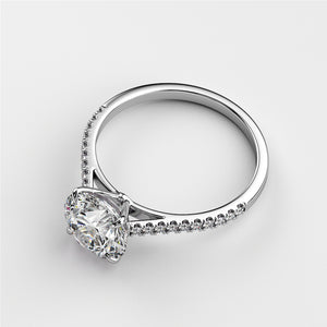 Elegant 14K or 18K white gold engagement ring with round solitaire diamond and pave accents, not worn on model.