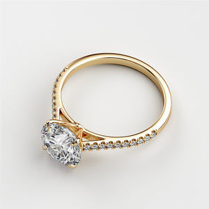 Elegant yellow gold engagement ring featuring an oval diamond center stone and delicate side diamonds, set in 14K or 18K.