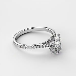 Close-up of a white gold oval solitaire engagement ring with pave detailing, featuring a pear-shaped diamond. Available in 14K, 18K, or platinum.