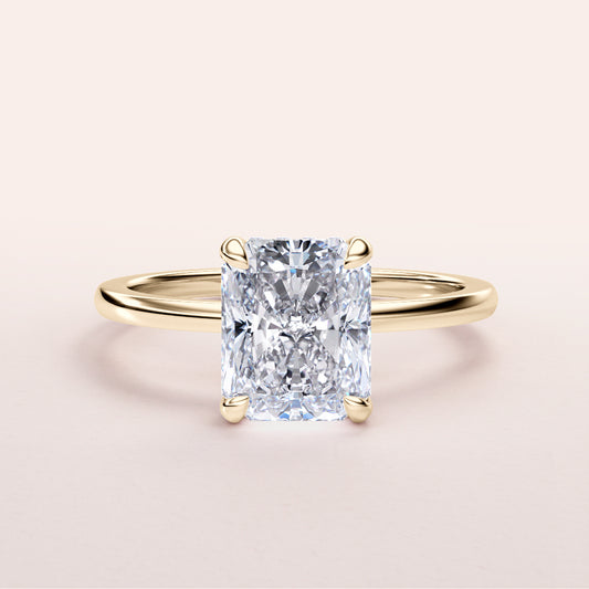 Radiant cut diamond ring in 14K or 18K yellow gold, elegantly set in a hidden halo design, on a plain background.