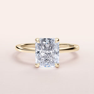 Radiant cut diamond ring in 14K or 18K yellow gold, elegantly set in a hidden halo design, on a plain background.