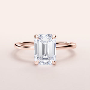 Elegant rose gold emerald cut diamond solitaire ring in 14K or 18K, featuring a hidden halo and a minimalist design.