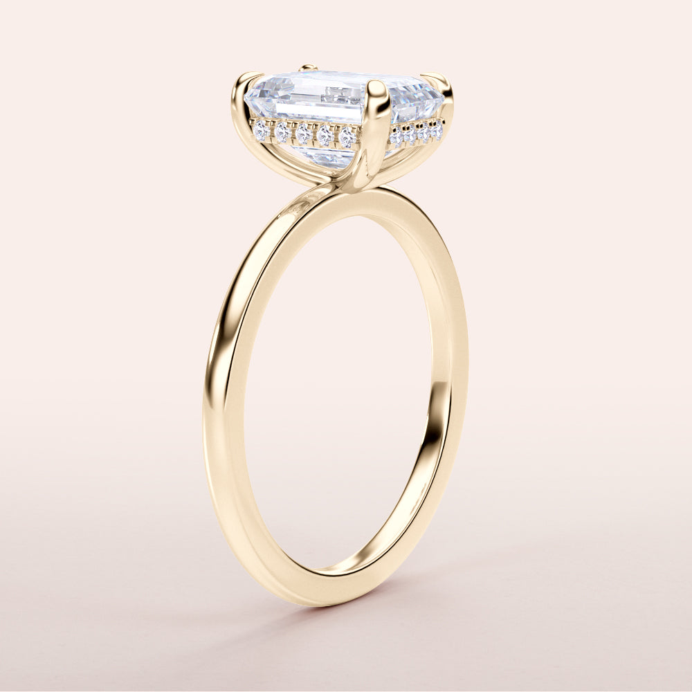 Elegant 14K yellow gold emerald hidden halo engagement ring with a classic plain band, not worn on model.