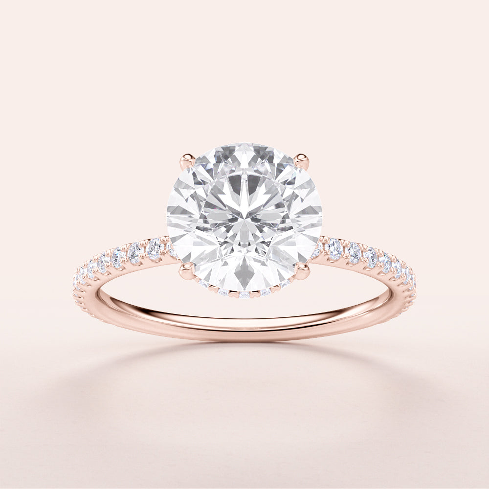 Elegant rose gold engagement ring with round diamond and pave band, available in 14K and 18K options. Timeless luxury.