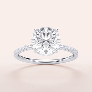 Elegant round brilliant-cut diamond engagement ring with a diamond-studded band in 14K or 18K white gold or platinum.