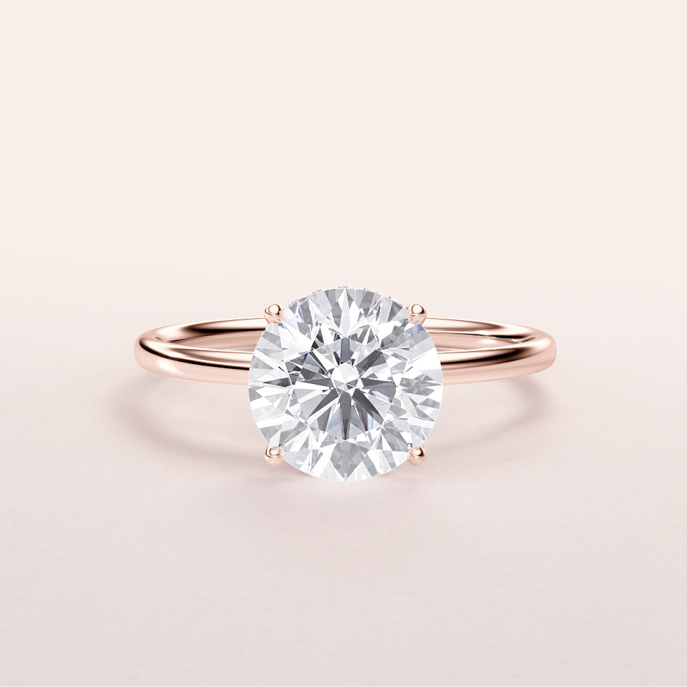 Elegant round diamond solitaire engagement ring in a 14K rose gold band, featuring a stunning hidden halo design.