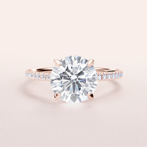 Stunning 14K rose gold engagement ring with round brilliant cut diamond and pave band, featuring a hidden halo of smaller diamonds.