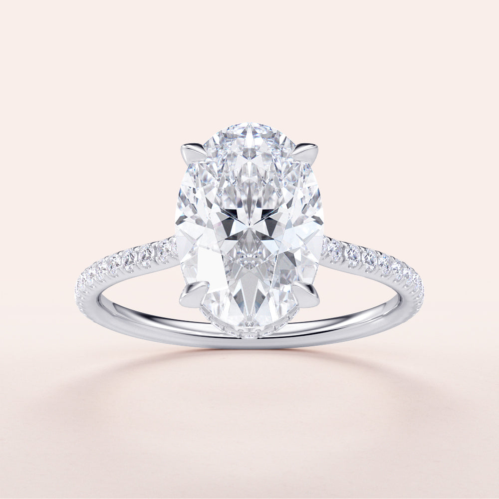 "Elegant 14K or 18K white gold engagement ring with oval diamond center, featuring an invisible gallery and sparkling pave band."