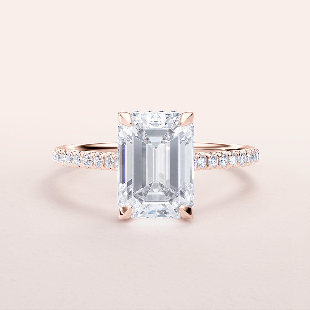 Elegant emerald-cut diamond engagement ring in rose gold, adorned with smaller diamonds. Available in 14K, 18K, and platinum.

#14KRecycledRoseGold
#18KRecycledRoseGold