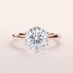 Close-up of a round brilliant-cut diamond solitaire engagement ring in rose gold, set in a sleek band, available in 14K, 18K, or platinum.