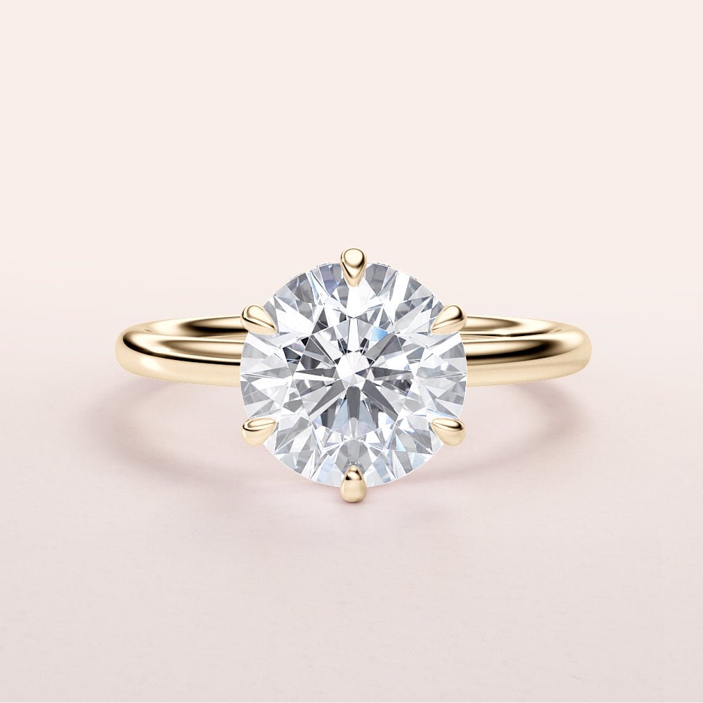 Elegant yellow gold engagement ring featuring a round diamond solitaire in a six-prong setting. Available in 14K and 18K.
