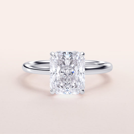 Radiant cut diamond solitaire engagement ring in 14K white gold, showcasing a sleek band against a neutral background.