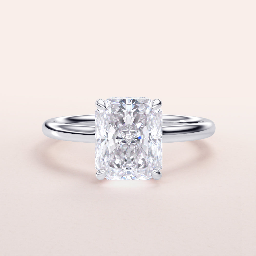 Radiant cut diamond solitaire engagement ring in 14K white gold, showcasing a sleek band against a neutral background.