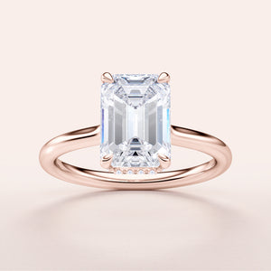 Elegant emerald engagement ring in lustrous 14K rose gold, featuring a hidden halo and plain band. Available in 18K and platinum.