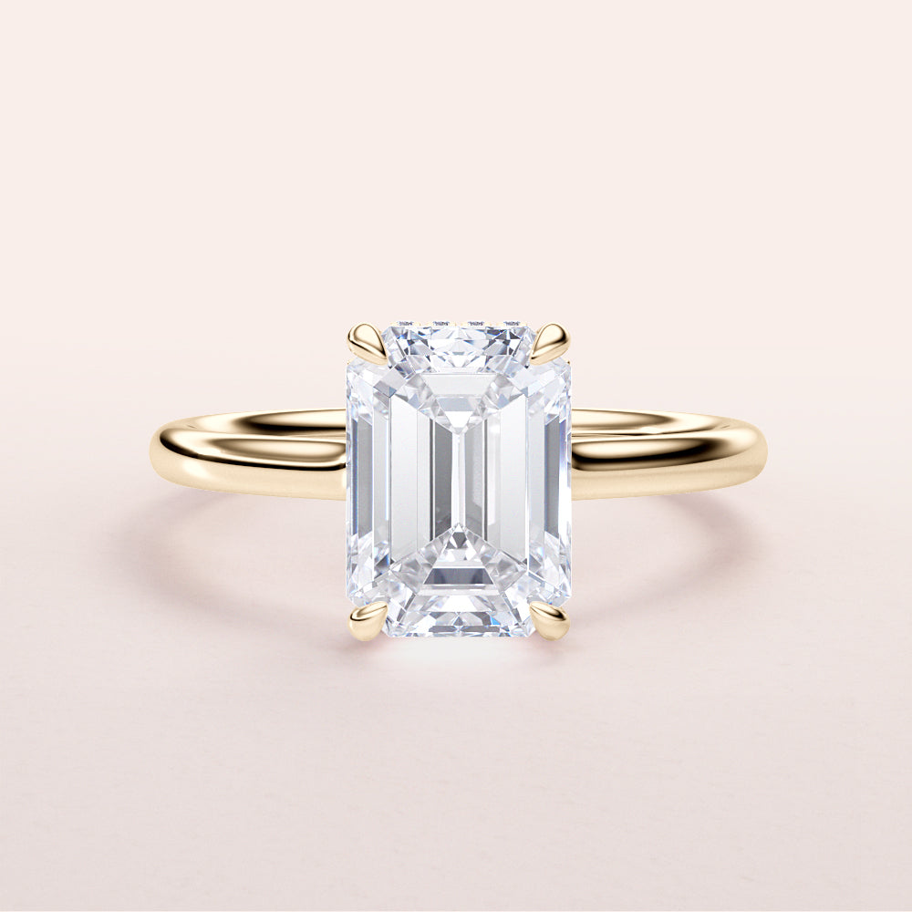 Elegant emerald-cut ring in 14K yellow gold, featuring an invisible gallery and hidden halo on a sleek plain band.