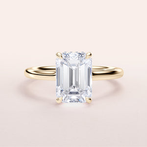 Elegant emerald-cut ring in 14K yellow gold, featuring an invisible gallery and hidden halo on a sleek plain band.