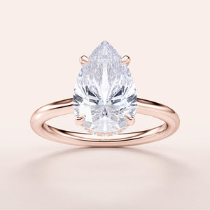 14K rose gold engagement ring featuring a pear-shaped diamond in solitaire setting. Elegant close-up of the hidden halo design.