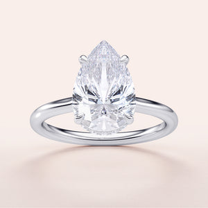 14K white gold solitaire engagement ring featuring a pear-shaped diamond with an invisible gallery and hidden halo.