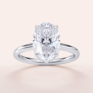 Elegant oval-cut diamond engagement ring in 14K/18K gold or platinum, featuring a sleek band and a hidden halo setting.