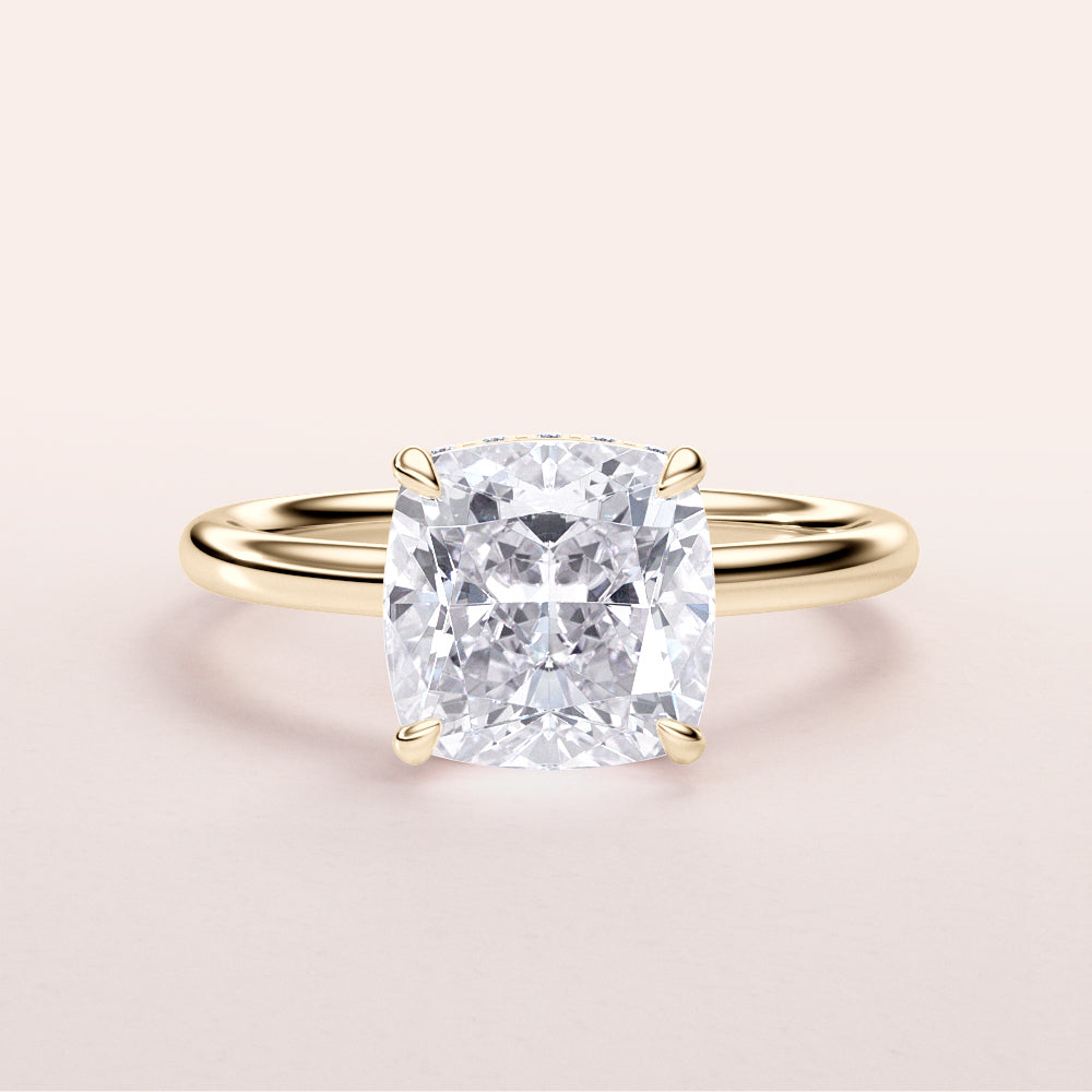 Elegant 14K/18K gold cushion-cut diamond engagement ring with hidden halo, featured on a minimalist background.