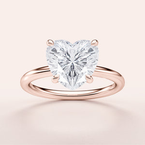 Elegant heart-shaped diamond engagement ring in 14K or 18K rose gold, showcasing a sparkling solitaire heart-cut diamond.