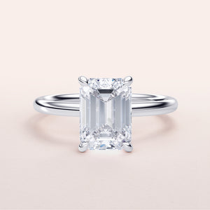 Emerald-cut diamond solitaire engagement ring in 14K, 18K gold, or platinum setting, elegant design on a light background.