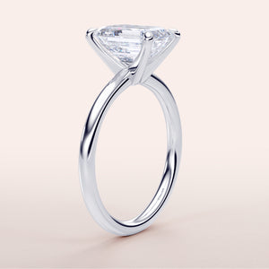 Platinum or 14K/18K white gold engagement ring with a stunning emerald, set in a minimalist band design, classic elegance.