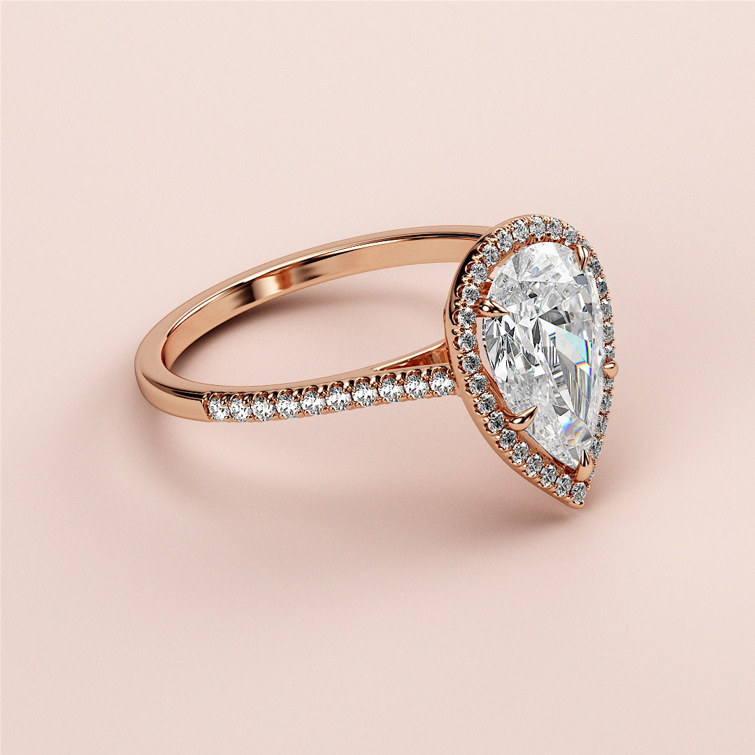 Elegant 14K rose gold engagement ring featuring a stunning pear-shaped diamond with a halo of smaller diamonds on a soft blush background.