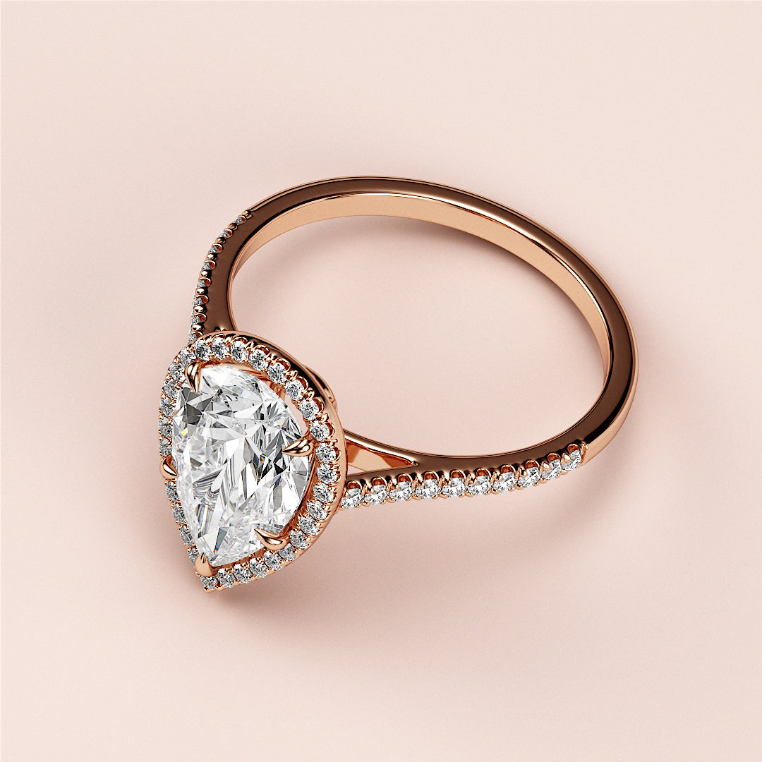 Elegant rose gold engagement ring with pear-shaped diamond center, halo, and pave band. Available in 14K, 18K, and platinum.