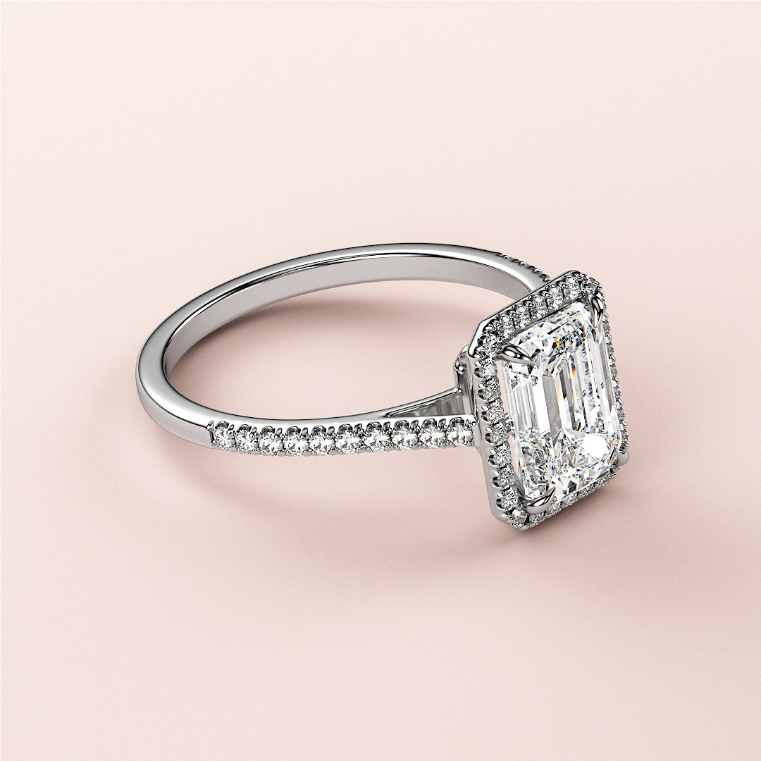 Stunning halo engagement ring with emerald-cut diamond and micropavÃ© band, available in 14K or 18K gold or platinum.