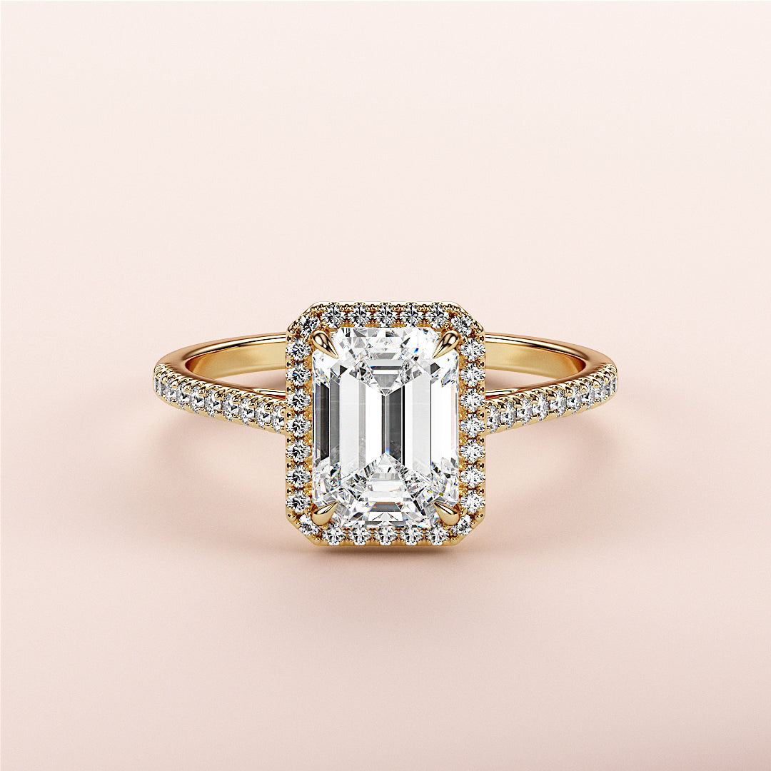 Emerald-cut diamond engagement ring with halo setting in 14K yellow gold, featuring a brilliant centerpiece and sparkling band.