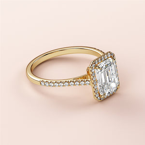 Elegant emerald-cut diamond ring in 14K yellow gold, featuring a sparkling halo and pave band, ideal for engagements.