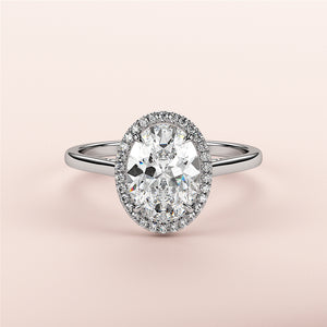 Elegant oval diamond halo engagement ring in white gold, available in 14K, 18K, or platinum, set against a soft pink background.