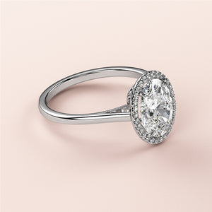 Elegant 14K white gold oval-cut diamond ring with halo setting, displayed on a model's finger. Timeless bridal jewelry.