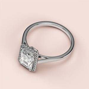A close-up of a radiant halo engagement ring featuring a princess-cut diamond, set in 14K or 18K white gold or platinum.