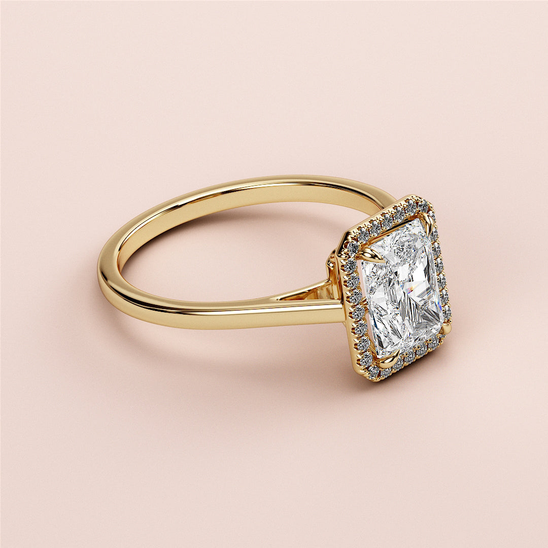 Elegant 14K yellow gold engagement ring featuring a radiant cut diamond in a halo, set against a soft peach background.|




#14KRecycledYellowGold
#18KRecycledYellowGold





