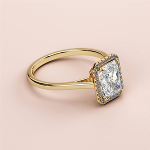 Elegant 14K yellow gold engagement ring featuring a radiant cut diamond in a halo, set against a soft peach background.