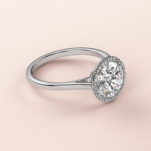 Elegant 14K white gold engagement ring with a halo setting, featuring an oval-cut diamond, on a light pink background.
