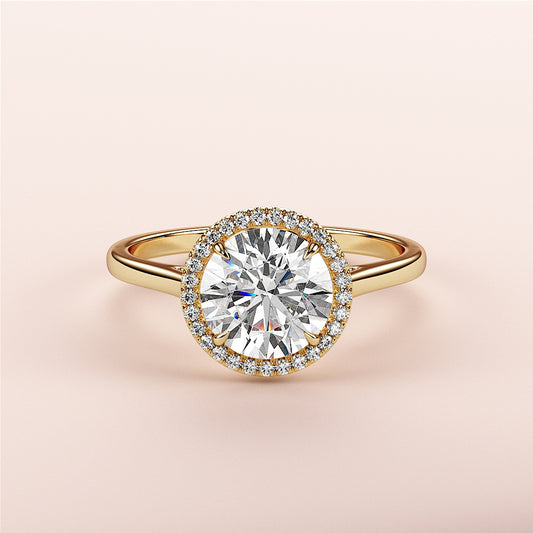 14K or 18K yellow gold engagement ring with round halo and cathedral band, featuring a diamond center stone, on pink background.