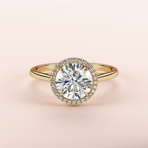 14K or 18K yellow gold engagement ring with round halo and cathedral band, featuring a diamond center stone, on pink background.