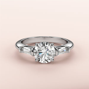 Elegant round diamond engagement ring with tapered baguette side stones in 14K/18K gold or platinum band.
