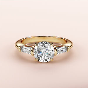 Elegant yellow gold engagement ring with round-cut diamond and tapered baguette accents, available in 14K, 18K, or platinum.