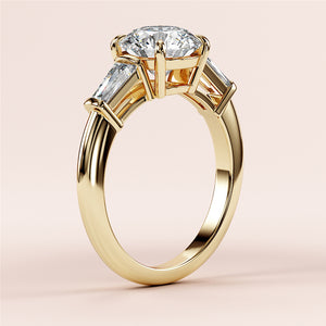 Elegant 14K gold engagement ring with round brilliant-cut diamond center and tapered baguette side stones, beautifully showcased.