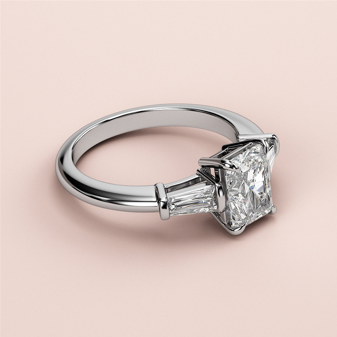 Elegant engagement ring featuring a radiant three stone tapered baguette design set in 14K white gold.