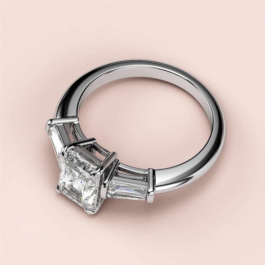 Elegant engagement ring with a radiant-cut diamond center and tapered baguette side diamonds in 14K or 18K white gold or platinum.