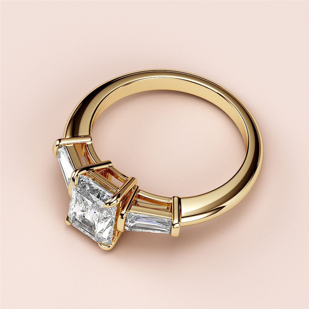 "14K or 18K yellow gold engagement ring featuring a radiant-cut diamond center stone and tapered baguette side stones."