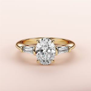 Elegant yellow gold engagement ring with an oval diamond and tapered baguettes, available in 14K, 18K, and platinum settings.