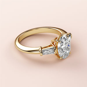 Elegant 14K yellow gold engagement ring featuring an oval-cut diamond and tapered baguette diamonds, not worn on a model.
