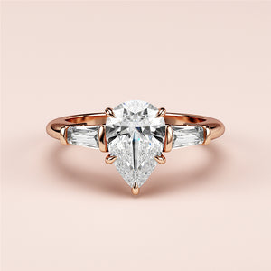 Elegant rose gold engagement ring featuring pear-shaped diamond and tapered baguette-cut side stones in 14K/18K or platinum setting.